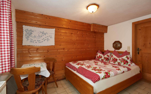 Gemütliches Schlafzimmer mit Holzverkleidung, Doppelbett und Sitzecke in der Almhütte Wagrain